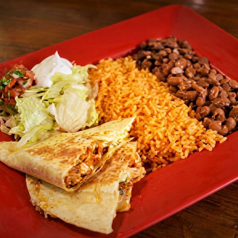 Chicken quesadilla with rice, beans, lettuce, pico de gallo, and sour cream on a red plate.